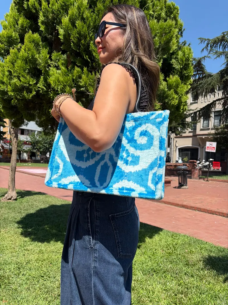 The blue ikat tote worn over the shoulder, seen from behind