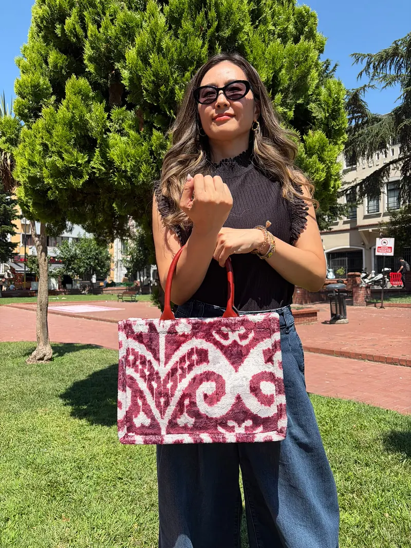 Madder-dyed bordeaux and ivory tote held at the front, carried by its tan handles