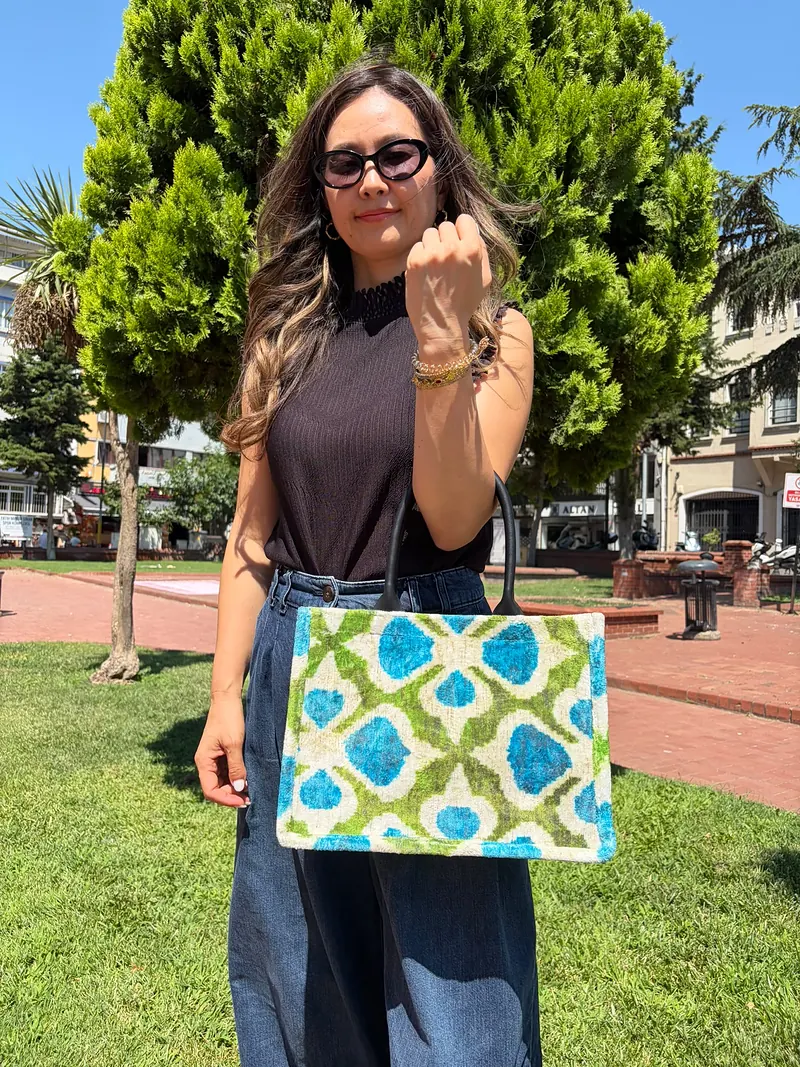Turquoise and moss garden-lattice kilim tote carried at the elbow
