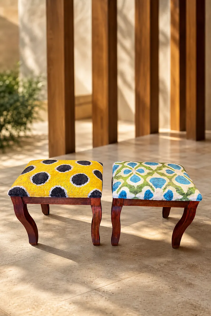 A pair of kilim stools with saffron and garden-lattice tops on walnut cabriole frames, beneath a wooden colonnade