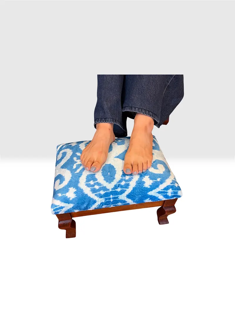 Bare feet resting on a stool top, showing its height against the floor